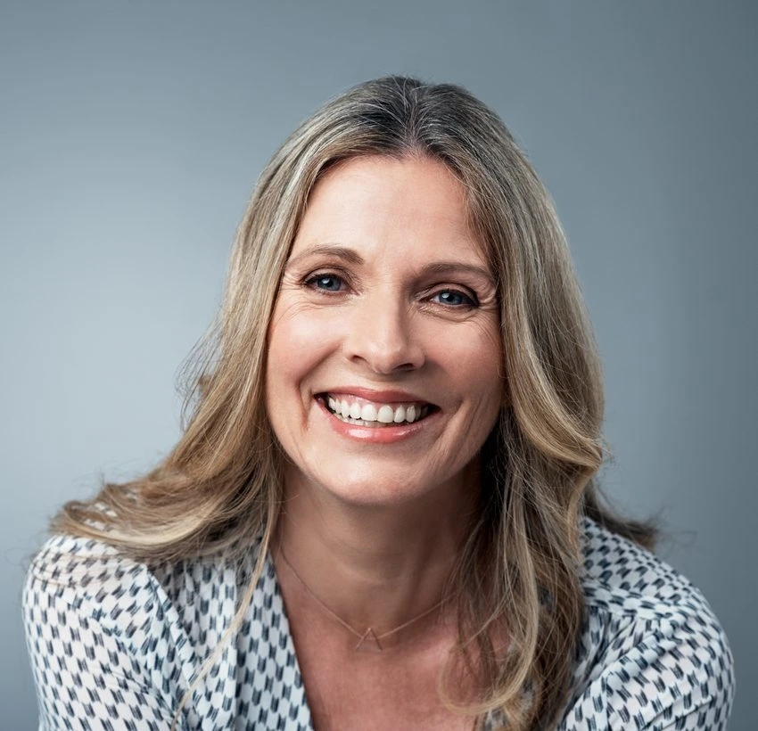 Professional headshot of a woman smiling against a blue background